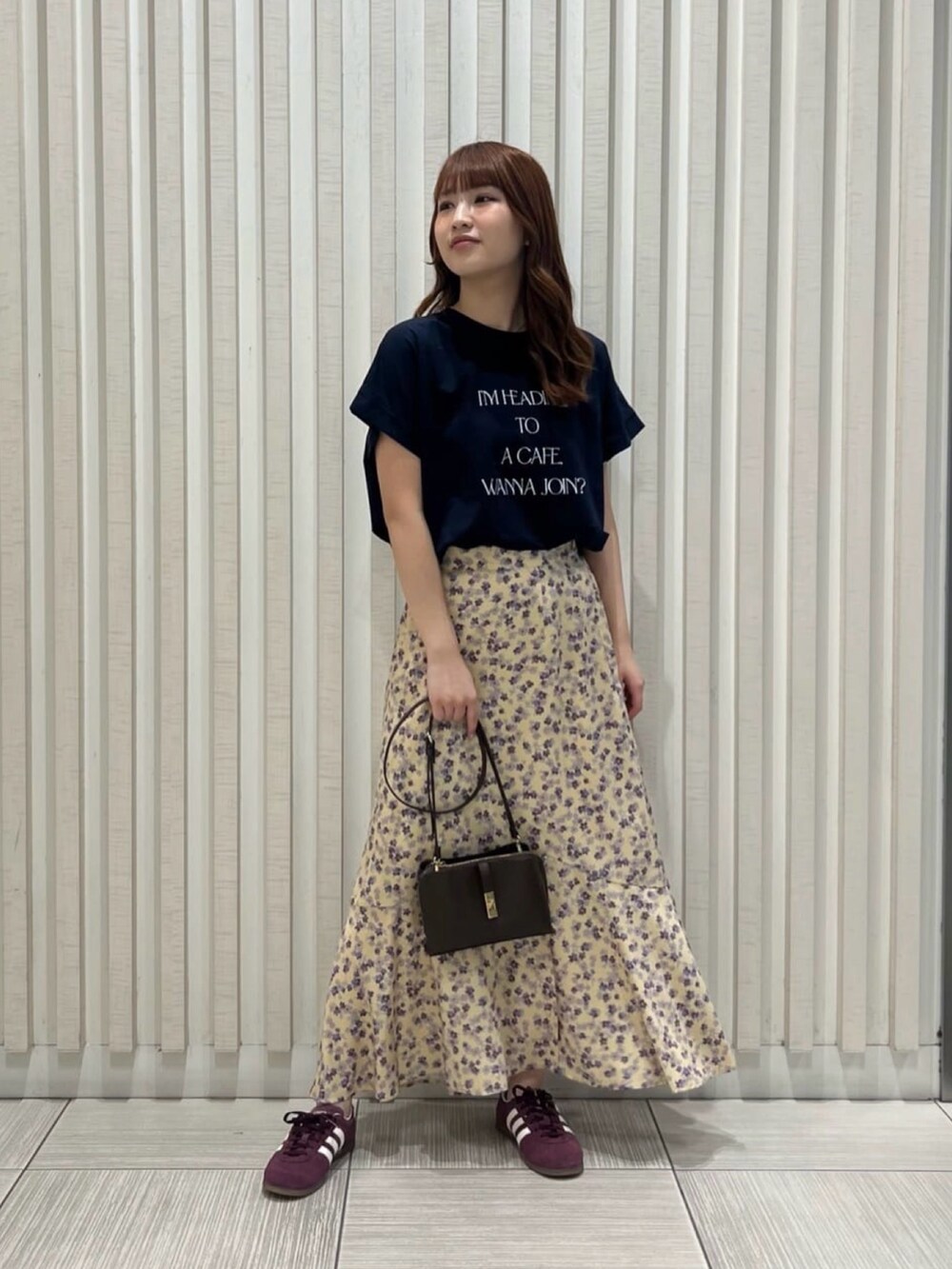 ブルー系のTシャツ/カットソー、イエロー系のスカート、ブラック系のショルダーバッグを着用したレディースの夏コーディネートの2枚目の写真