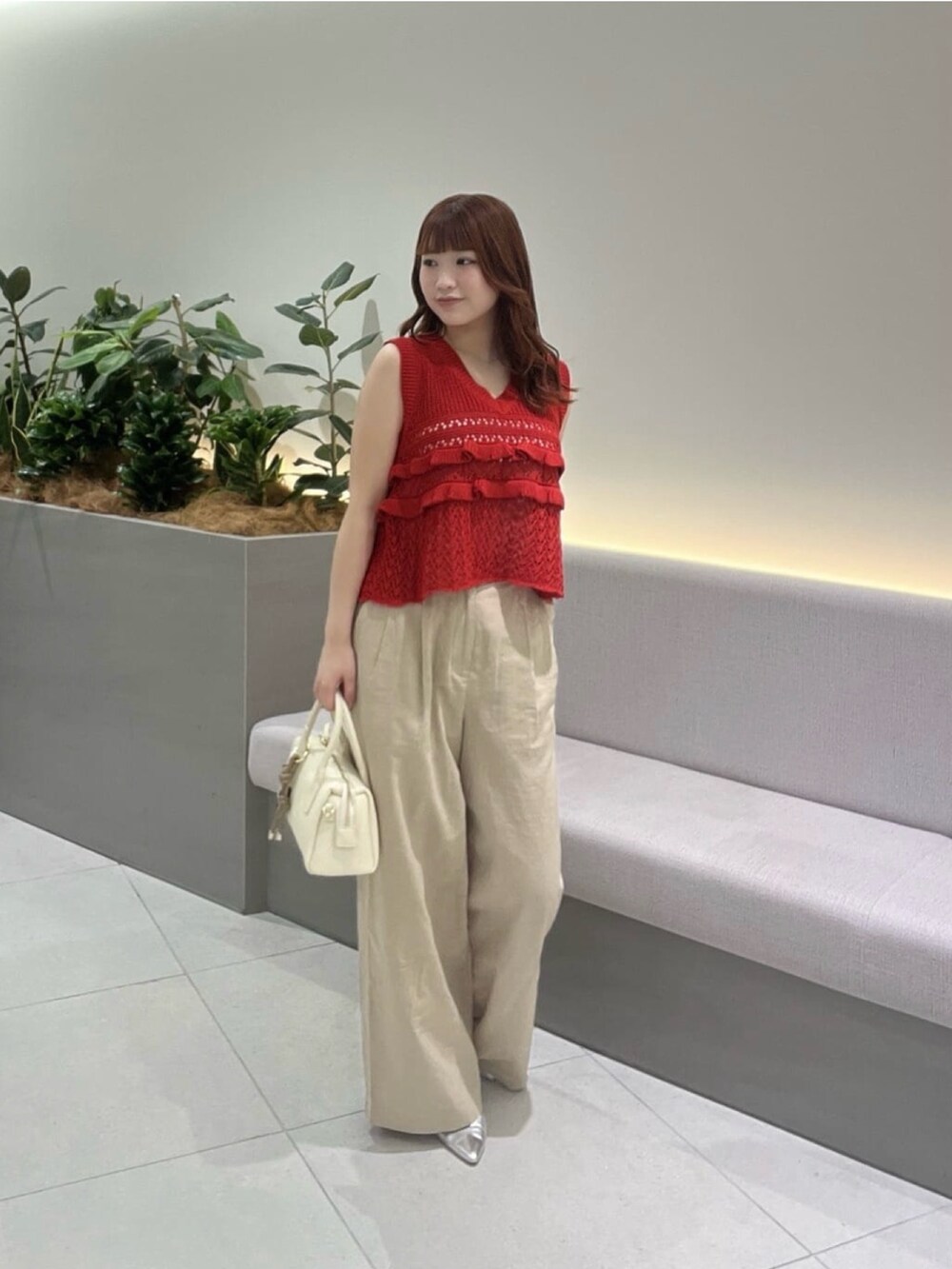 レッド系のニット/セーター、ベージュ系のその他パンツ、ブラウン系のボストンバッグを着用したレディースの夏コーディネートの2枚目の写真