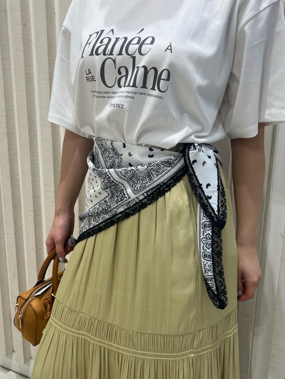 ホワイト系のTシャツ/カットソー、イエロー系のスカート、オレンジ系のボストンバッグを着用したレディースの夏コーディネートの7枚目の写真