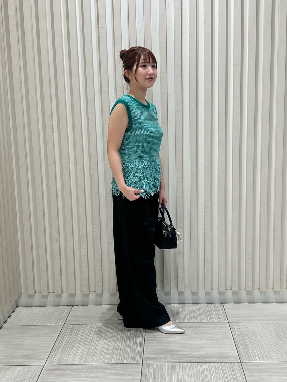 グリーン系のニット/セーター、ブラック系のその他パンツ、ブラウン系のボストンバッグを着用したレディースの夏コーディネートの4枚目の写真