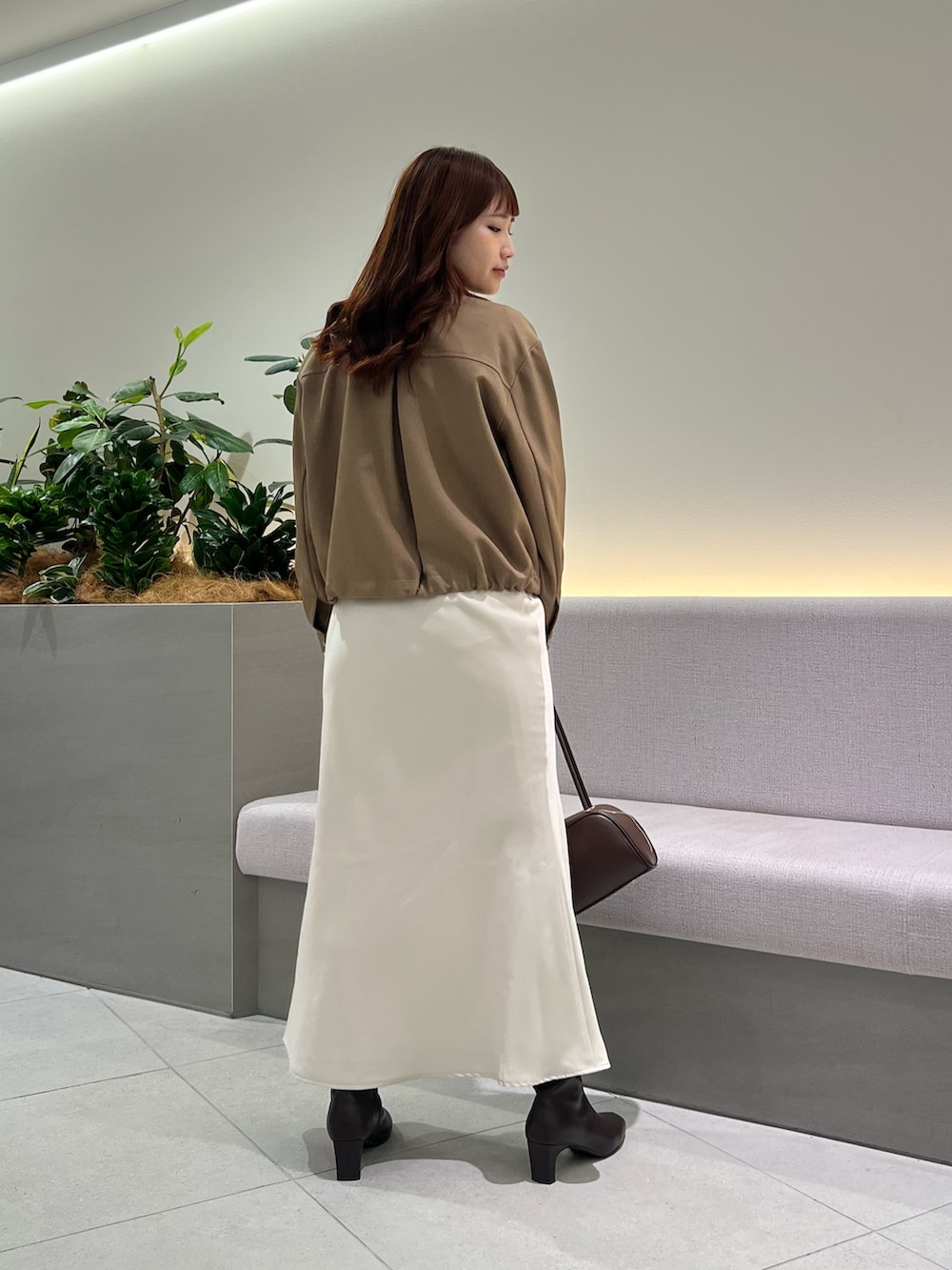 ブラウン系のブルゾン、ホワイト系のTシャツ/カットソー、ブラウン系のボストンバッグを着用したレディースの秋コーディネートの6枚目の写真