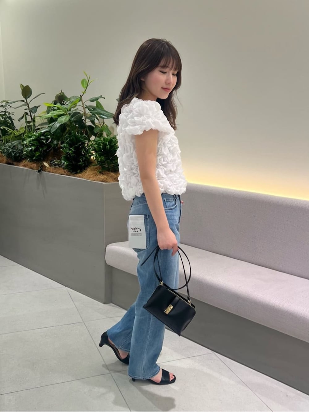 ブルー系のデニムパンツ、ホワイト系のシャツ/ブラウス、ブラック系のショルダーバッグを着用したレディースの夏コーディネートの3枚目の写真