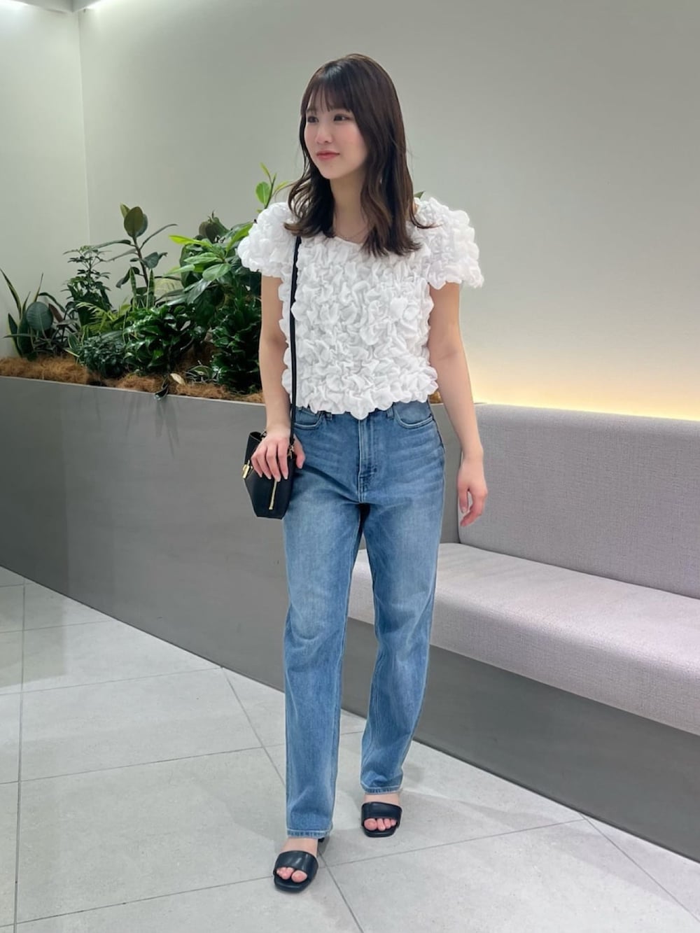 ブルー系のデニムパンツ、ホワイト系のシャツ/ブラウス、ブラック系のショルダーバッグを着用したレディースの夏コーディネートの2枚目の写真