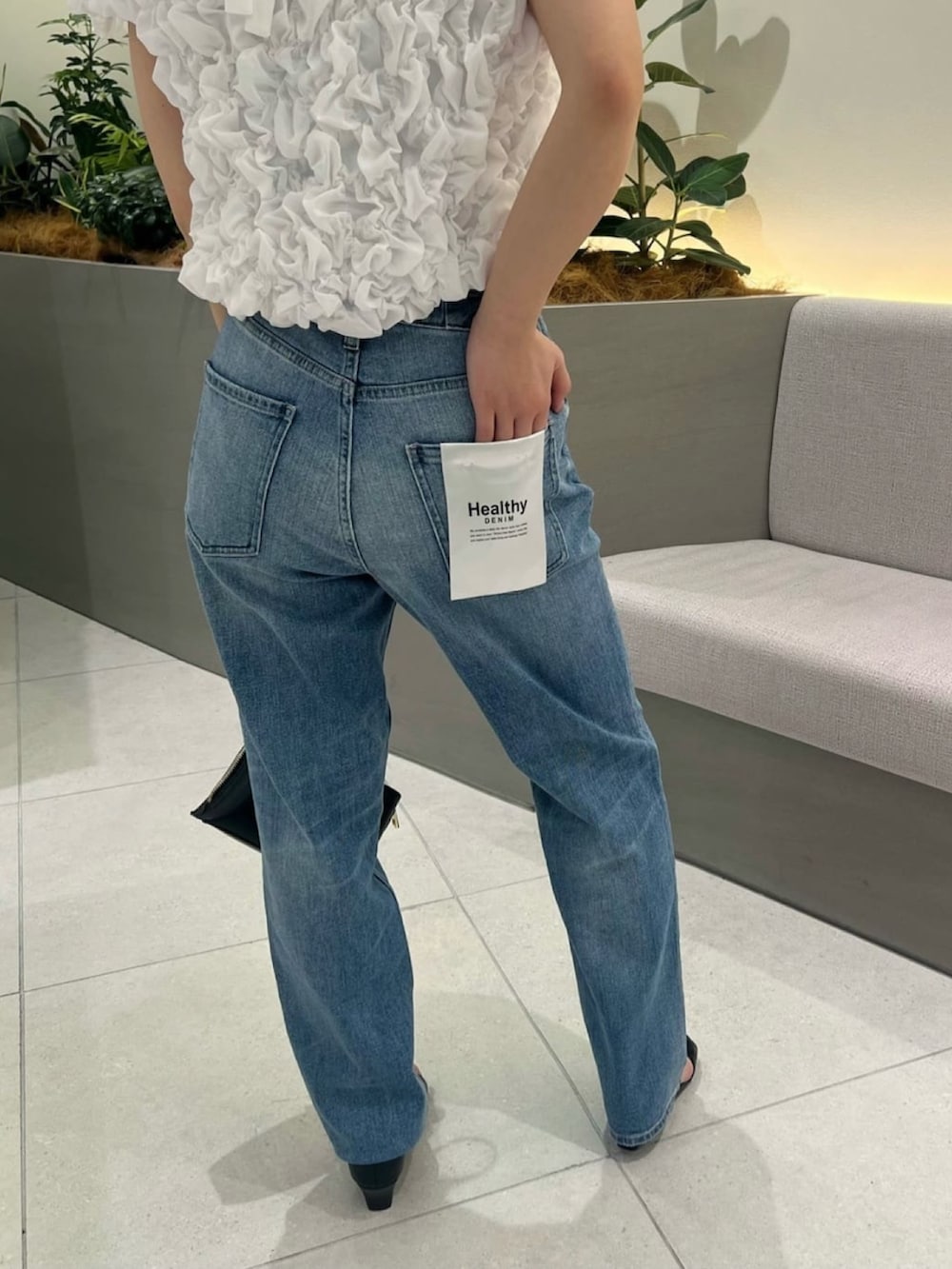 ブルー系のデニムパンツ、ホワイト系のシャツ/ブラウス、ブラック系のショルダーバッグを着用したレディースの夏コーディネートの5枚目の写真