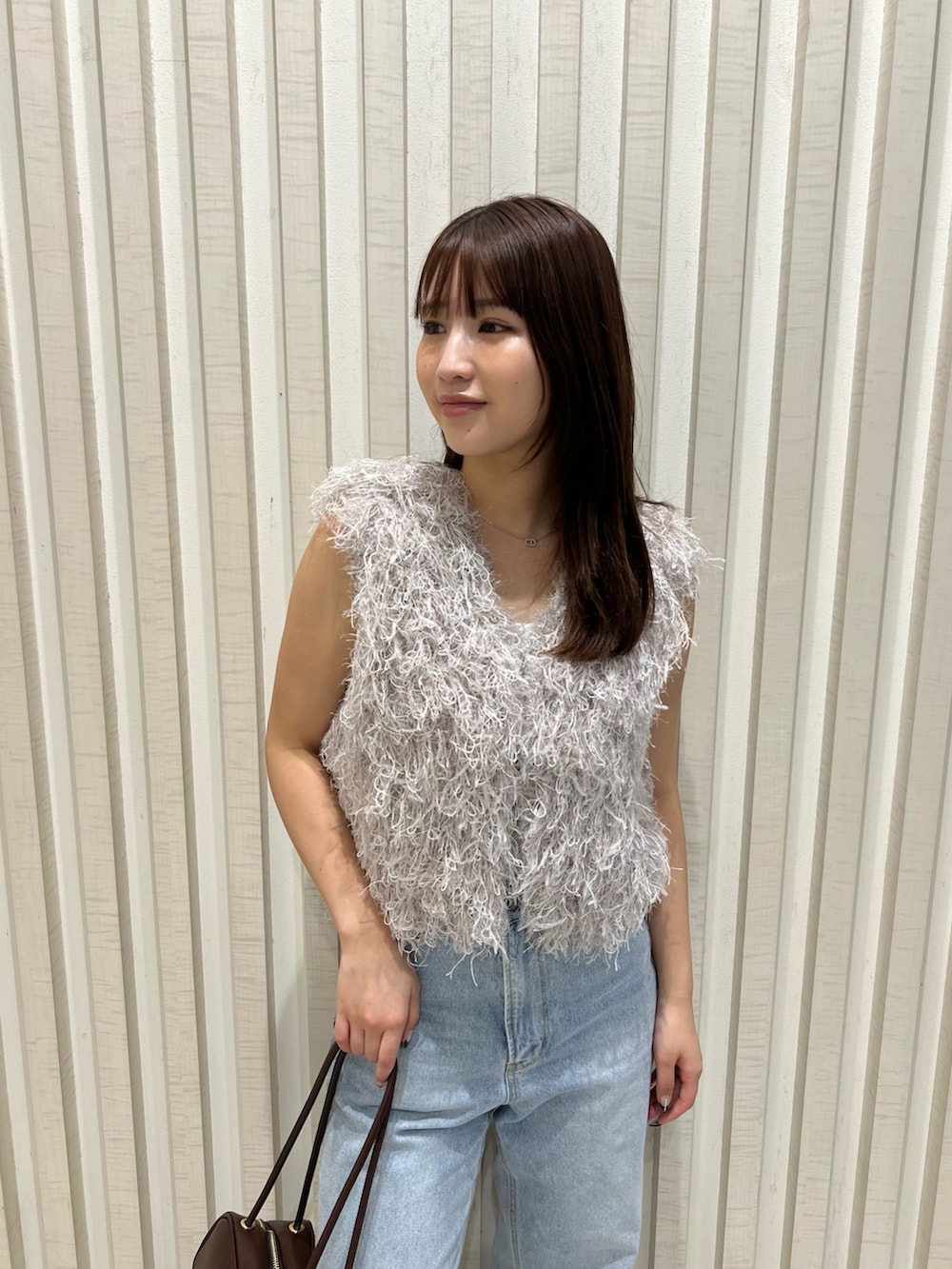 グレー系のベスト、ブルー系のデニムパンツ、ブラウン系のボストンバッグを着用したレディースの夏コーディネートの6枚目の写真
