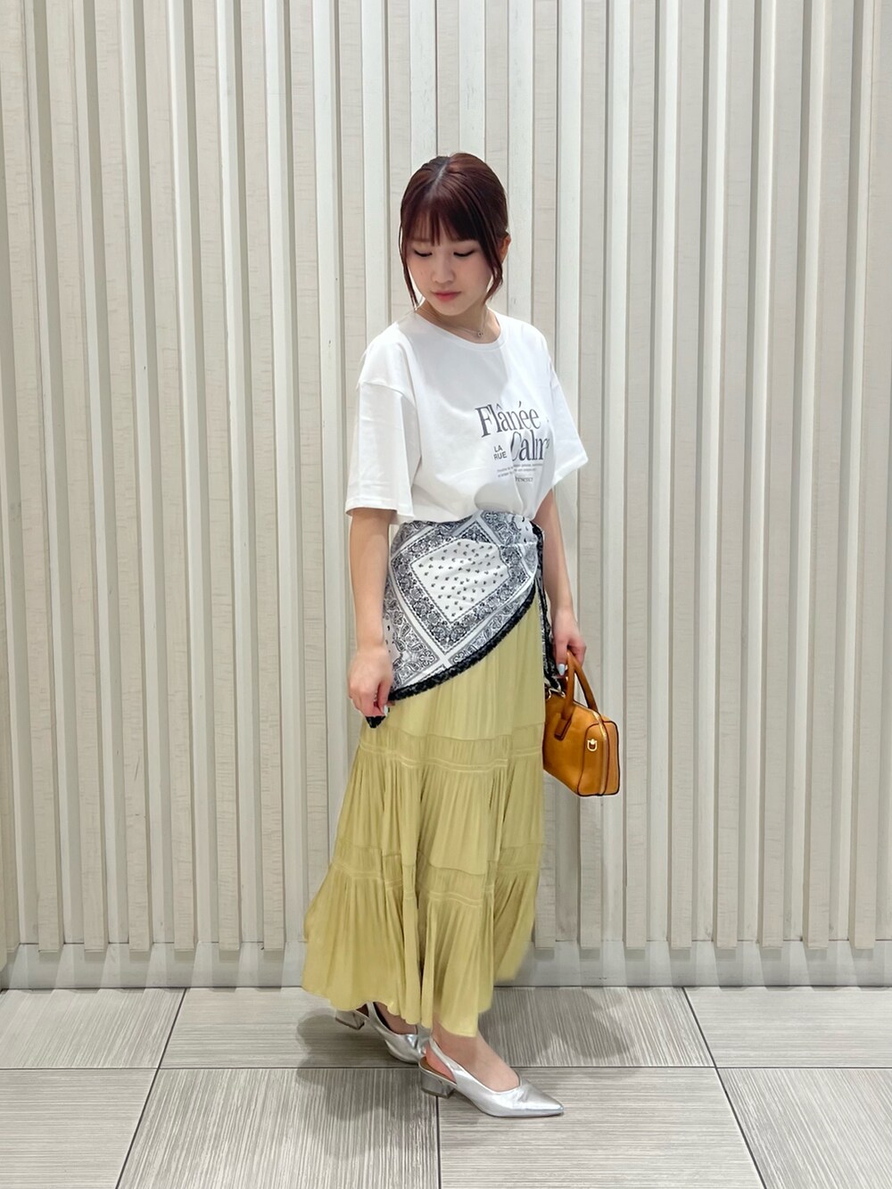 ホワイト系のTシャツ/カットソー、イエロー系のスカート、オレンジ系のボストンバッグを着用したレディースの夏コーディネートの3枚目の写真