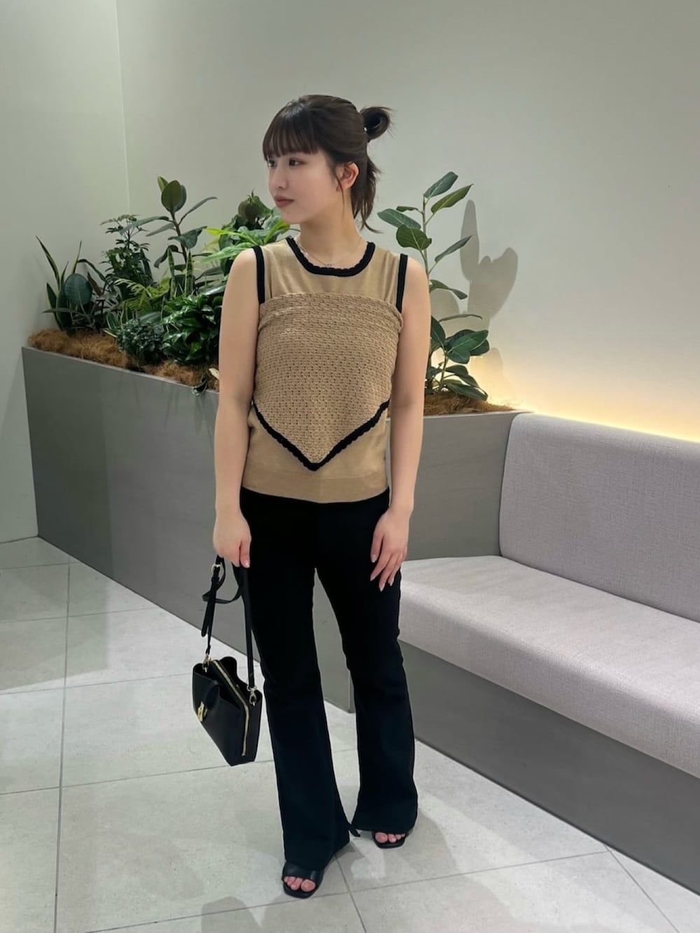 ベージュ系のニット/セーター、ブラック系のデニムパンツ、ブラック系のショルダーバッグを着用したレディースの夏コーディネートの2枚目の写真