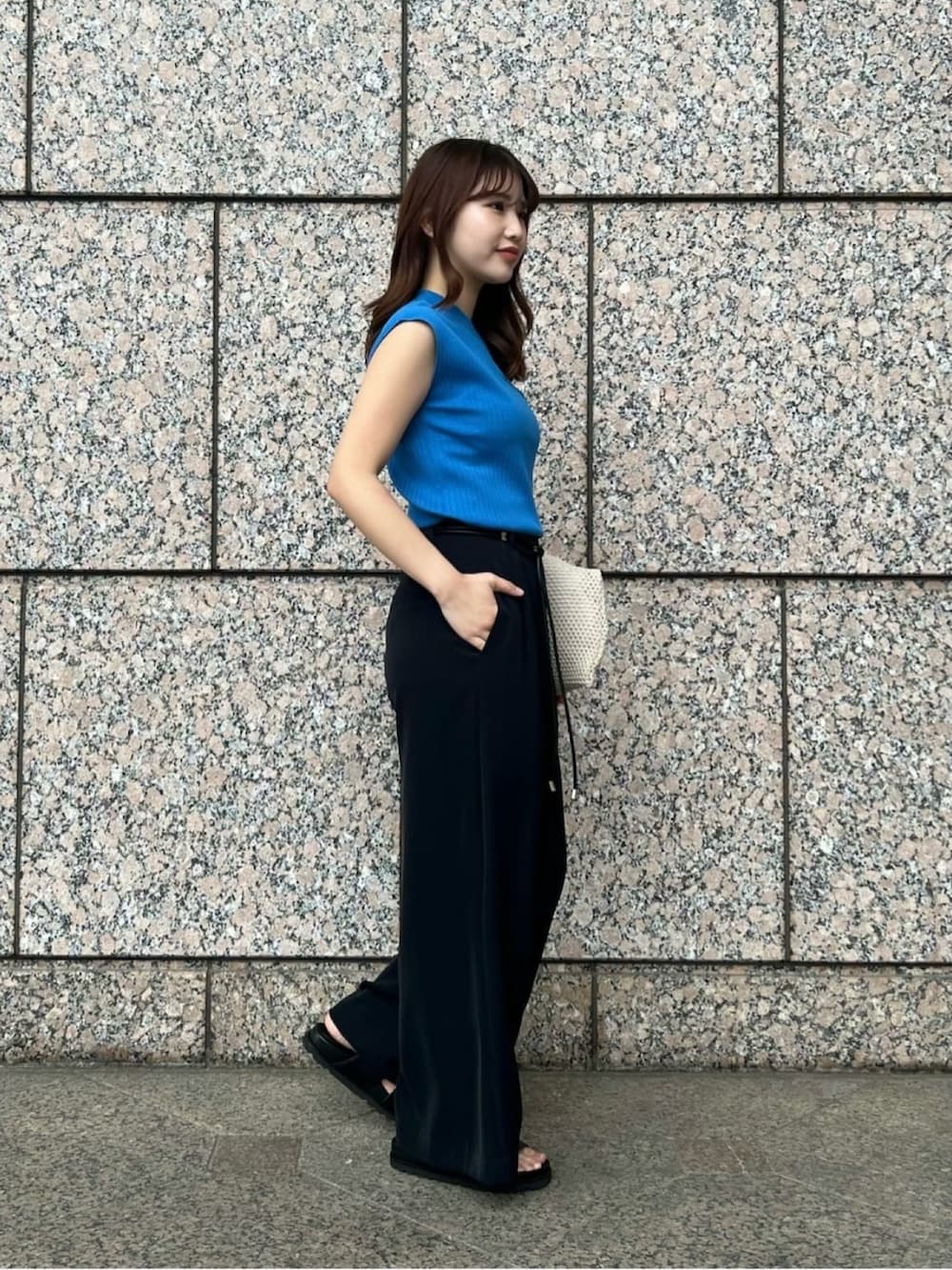 ブルー系のニット/セーター、ホワイト系のショルダーバッグ、ブラック系のその他パンツを着用したレディースの夏コーディネートの3枚目の写真