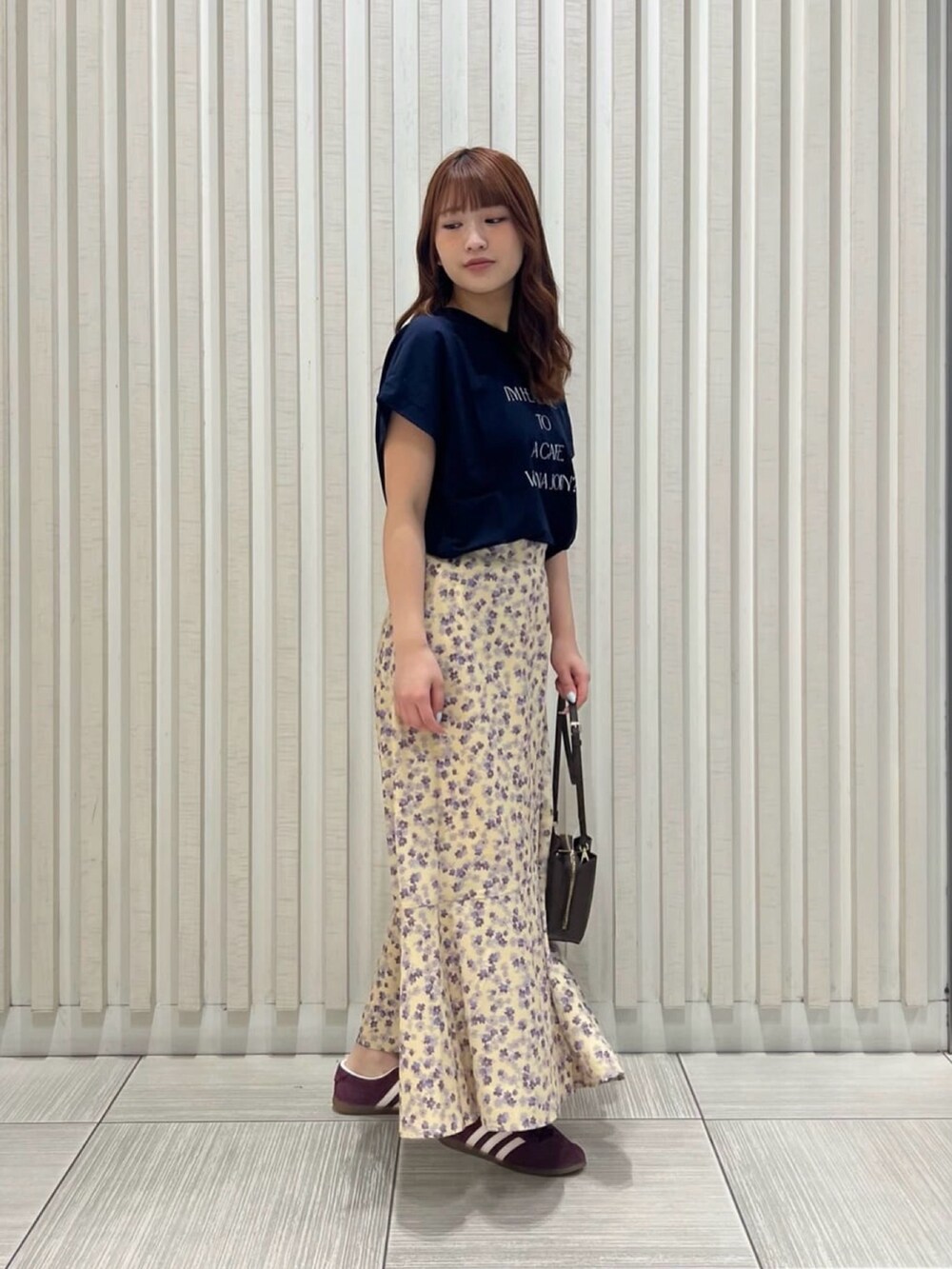 ブルー系のTシャツ/カットソー、イエロー系のスカート、ブラック系のショルダーバッグを着用したレディースの夏コーディネートの3枚目の写真