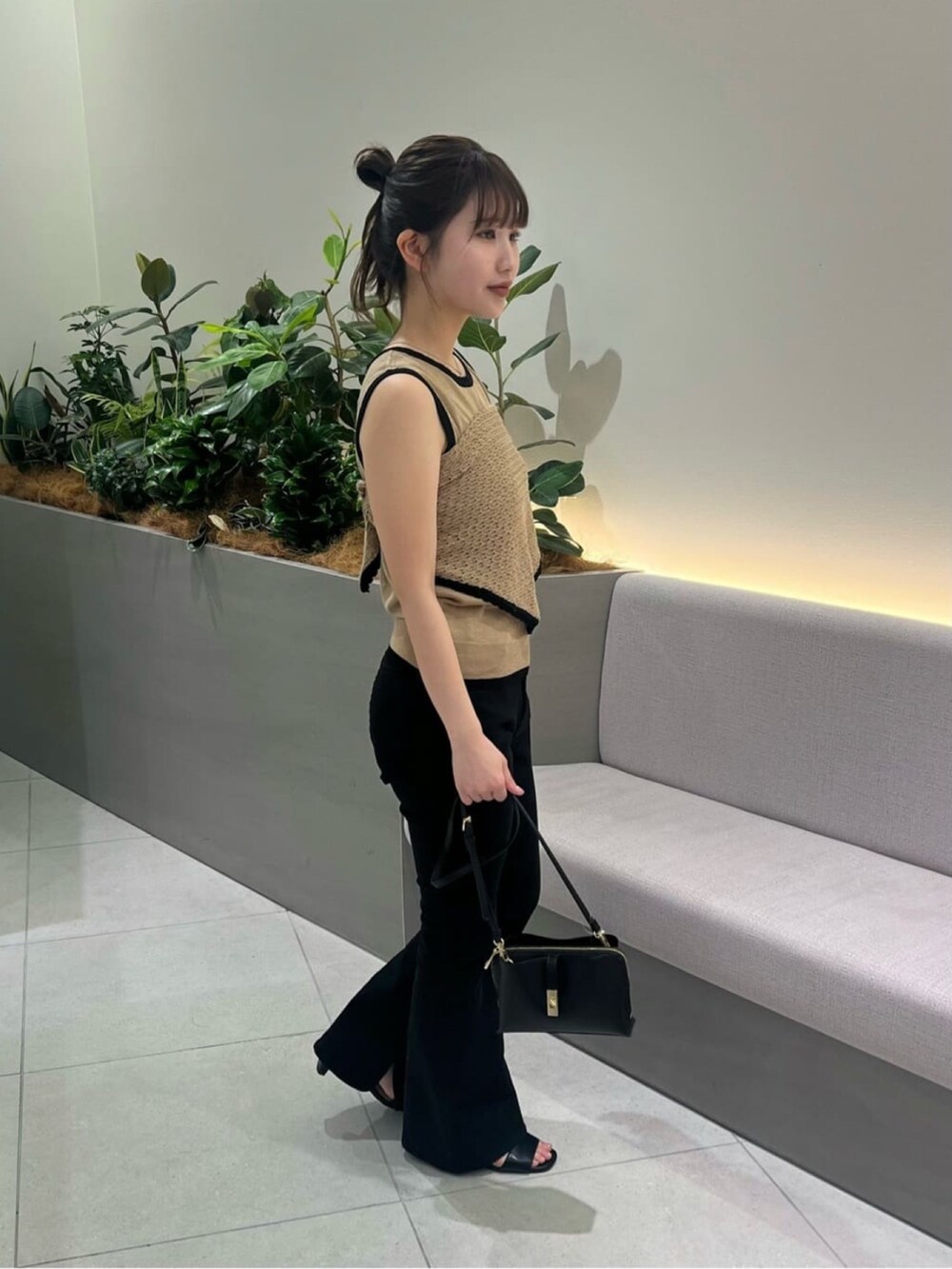 ベージュ系のニット/セーター、ブラック系のデニムパンツ、ブラック系のショルダーバッグを着用したレディースの夏コーディネートの5枚目の写真