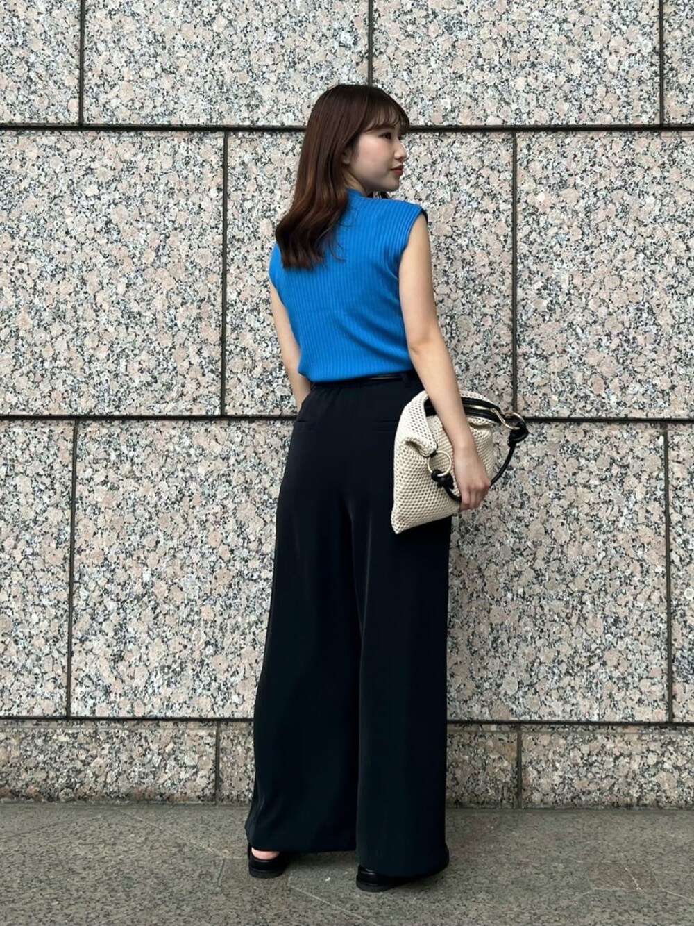 ブルー系のニット/セーター、ホワイト系のショルダーバッグ、ブラック系のその他パンツを着用したレディースの夏コーディネートの4枚目の写真