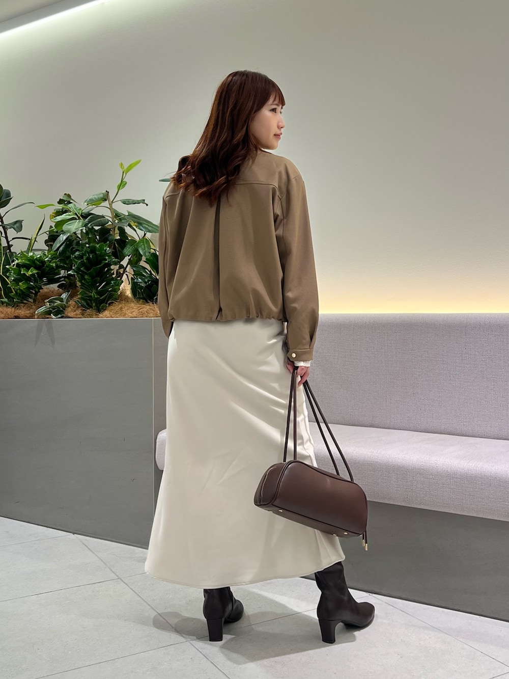 ブラウン系のブルゾン、ホワイト系のTシャツ/カットソー、ブラウン系のボストンバッグを着用したレディースの秋コーディネートの7枚目の写真