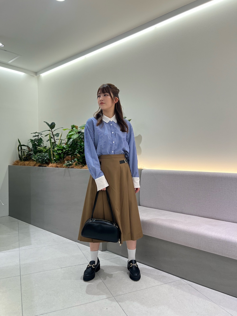 ブラック系のボストンバッグ、ブラック系のローファー、イエロー系のスカートを着用したレディースの夏コーディネートの2枚目の写真