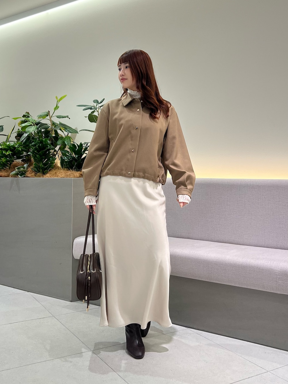 ブラウン系のブルゾン、ホワイト系のTシャツ/カットソー、ブラウン系のボストンバッグを着用したレディースの秋コーディネートの2枚目の写真
