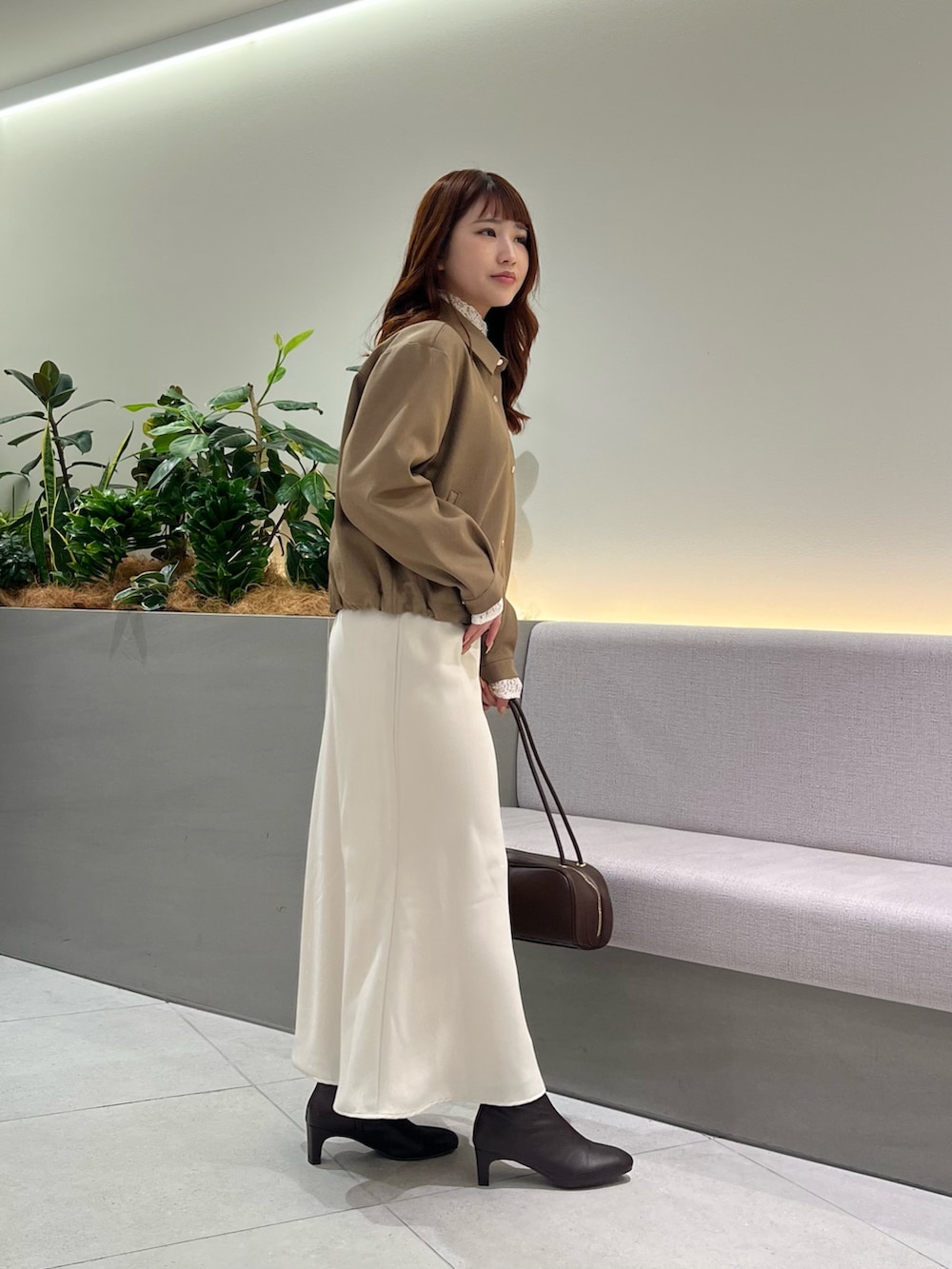 ブラウン系のブルゾン、ホワイト系のTシャツ/カットソー、ブラウン系のボストンバッグを着用したレディースの秋コーディネートの4枚目の写真