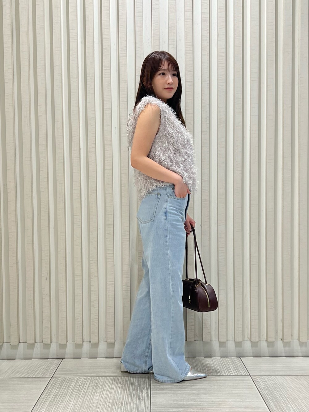 グレー系のベスト、ブルー系のデニムパンツ、ブラウン系のボストンバッグを着用したレディースの夏コーディネートの4枚目の写真