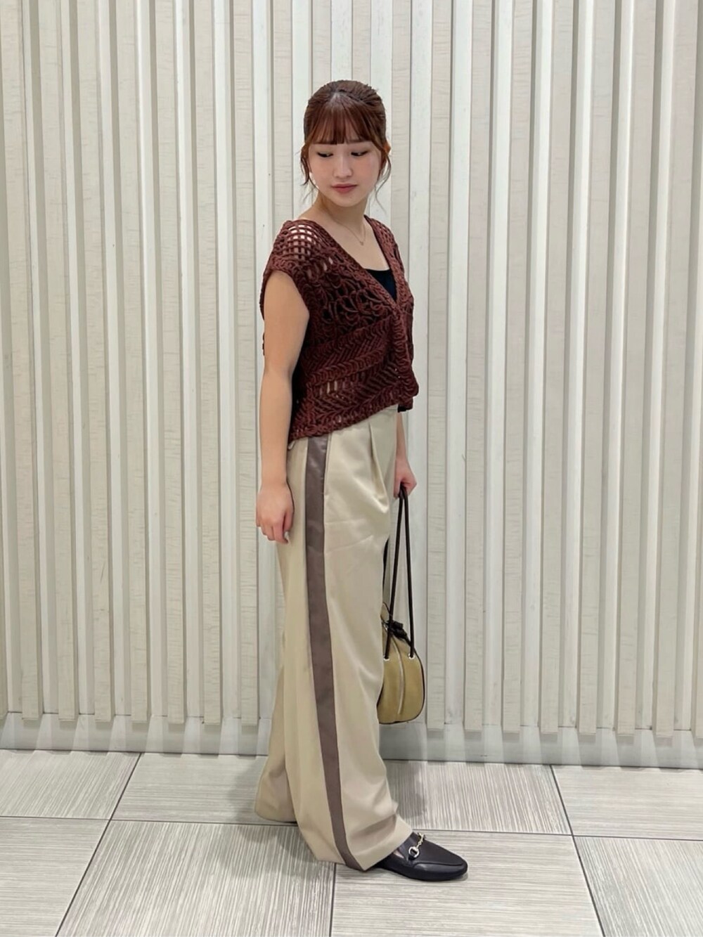 ベージュ系のその他パンツ、ブラウン系のベスト、ベージュ系のボストンバッグを着用したレディースの夏コーディネートの2枚目の写真
