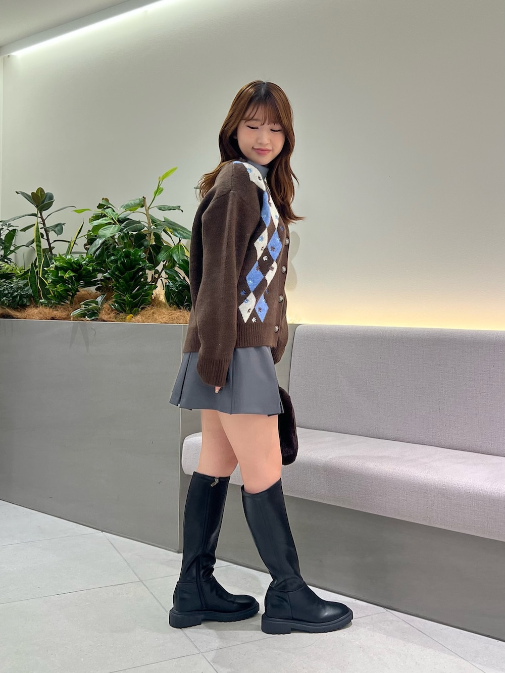 ブラウン系のカーディガン/ボレロ、ブルー系のTシャツ/カットソー、グレー系のスカートを着用したレディースの秋コーディネートの4枚目の写真