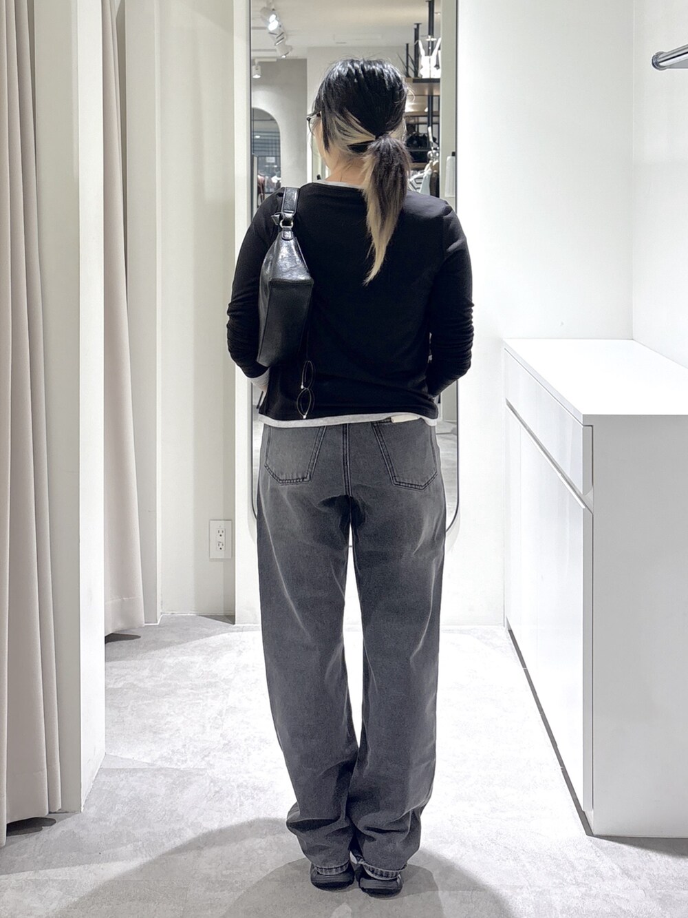 ブラック系のTシャツ/カットソー、ブラック系のデニムパンツ、ブラック系のショルダーバッグを着用したレディースの秋コーディネートの3枚目の写真