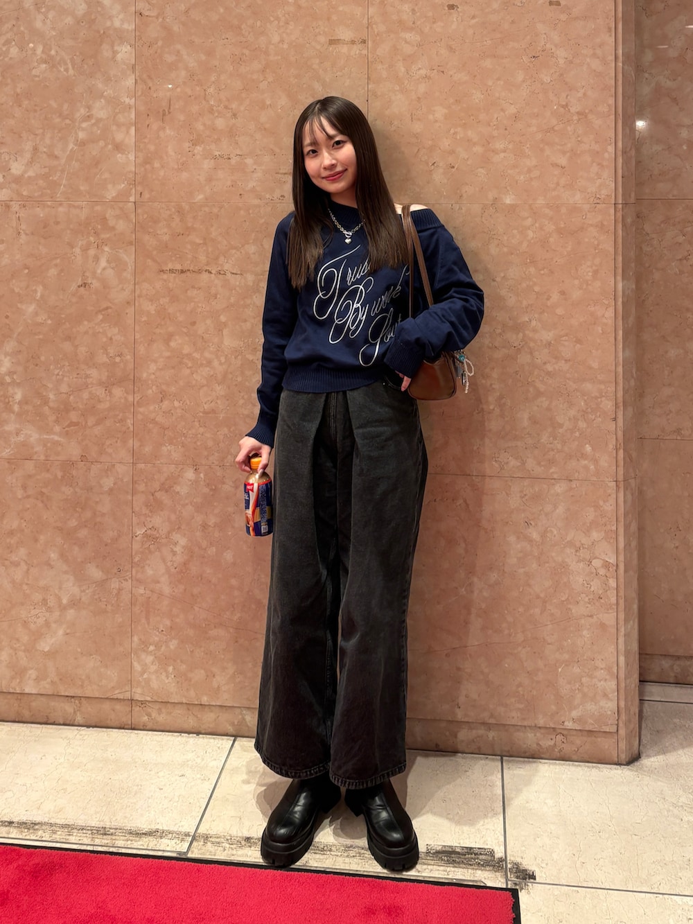 ブラック系のデニムパンツ、ブラック系のブーツ、ブラウン系のボストンバッグを着用したレディースの冬コーディネートの2枚目の写真