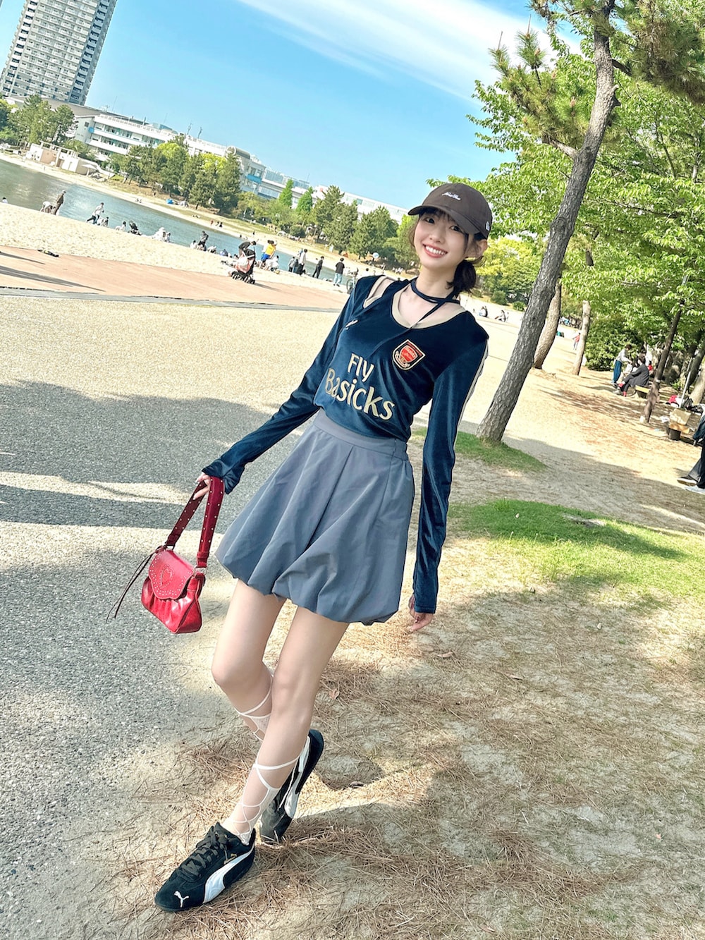 レッド系のショルダーバッグ、ブラック系のスニーカー、ブルー系のトップスを着用したレディースの秋コーディネートの2枚目の写真