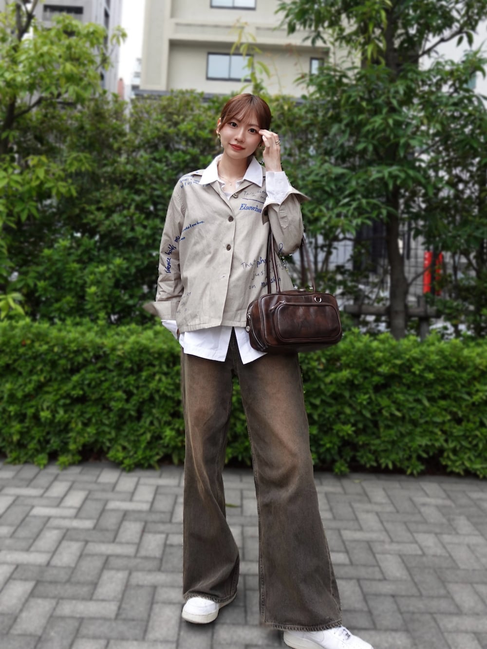 ブラウン系のデニムパンツ、ブラウン系のショルダーバッグ、ホワイト系のスニーカーを着用したレディースの秋コーディネートの2枚目の写真