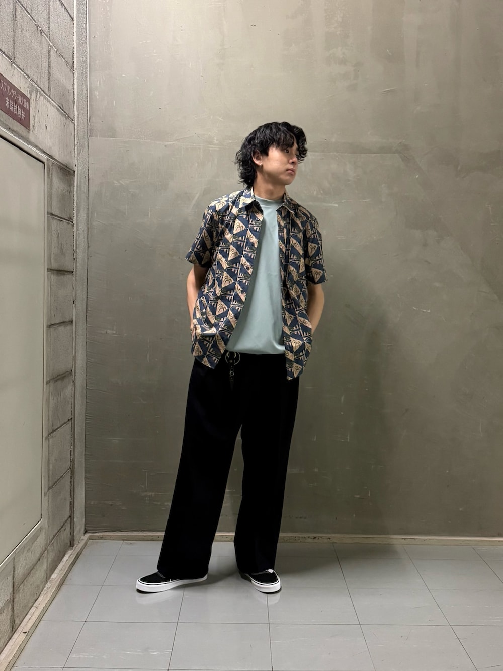 グリーン系のTシャツ/カットソー、ブラック系のスニーカーを着用したメンズの春コーディネートの2枚目の写真