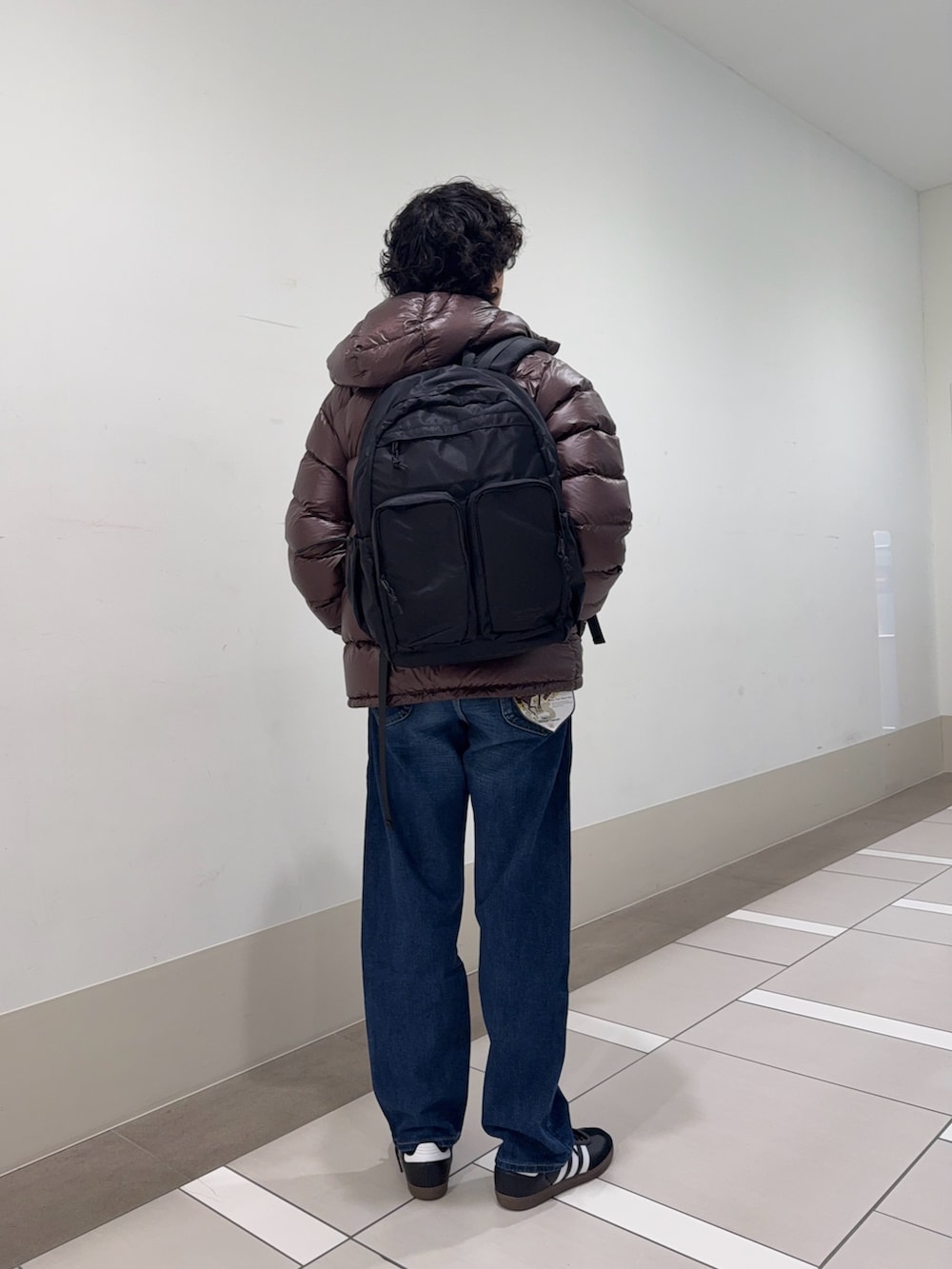 ブラウン系のダウンジャケット/コート、ホワイト系のニット/セーター、ブルー系のデニムパンツを着用したメンズの冬コーディネートの3枚目の写真