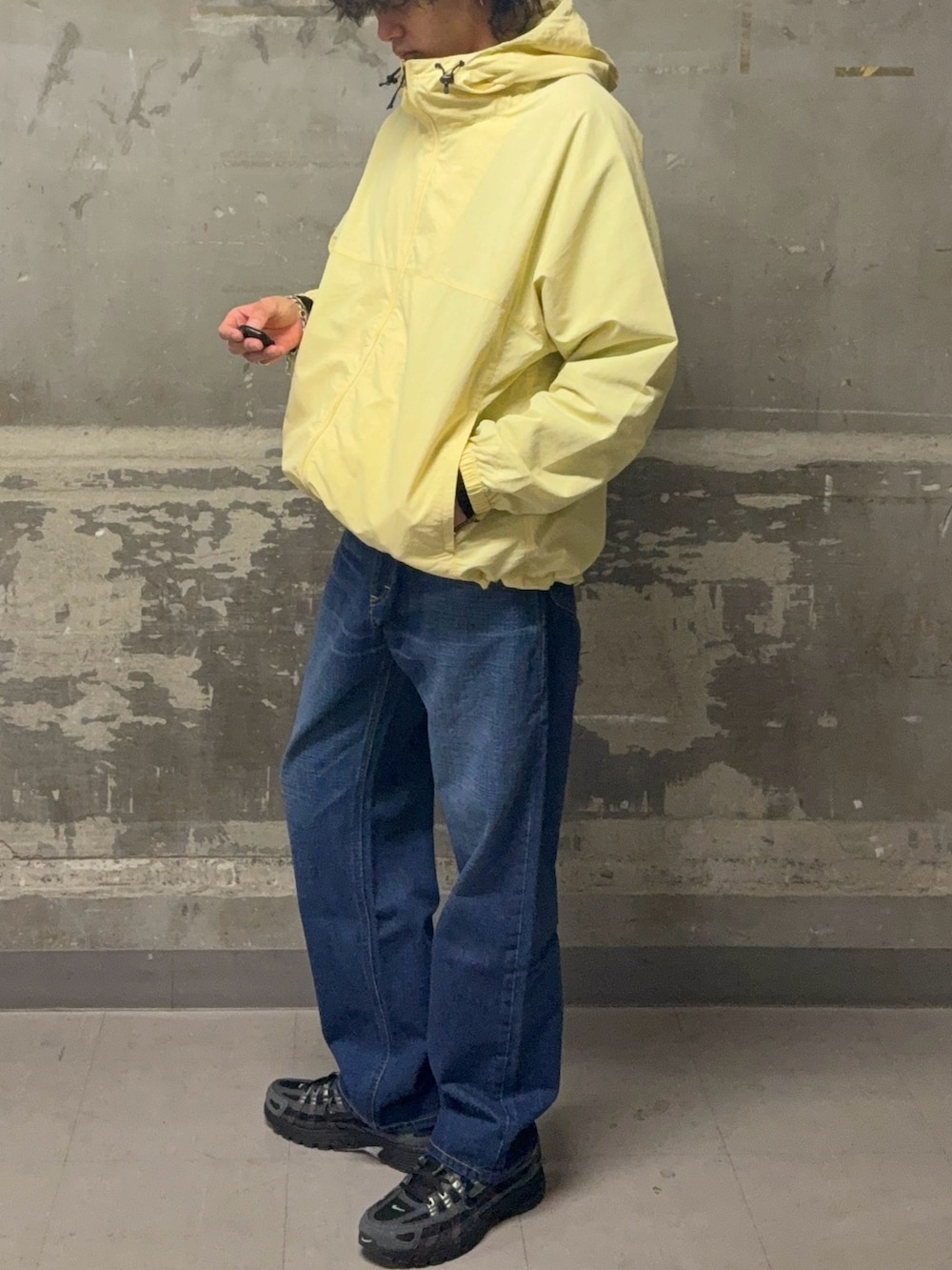 ブルー系のデニムパンツ、イエロー系のナイロンジャケット、ブラック系のスニーカーを着用したメンズの冬コーディネートの4枚目の写真