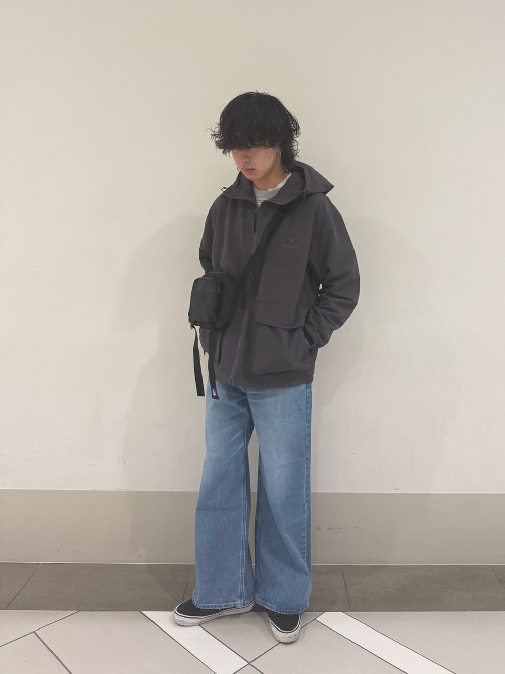 グレー系のマウンテンパーカー、ブルー系のデニムパンツを着用したメンズの冬コーディネートの2枚目の写真