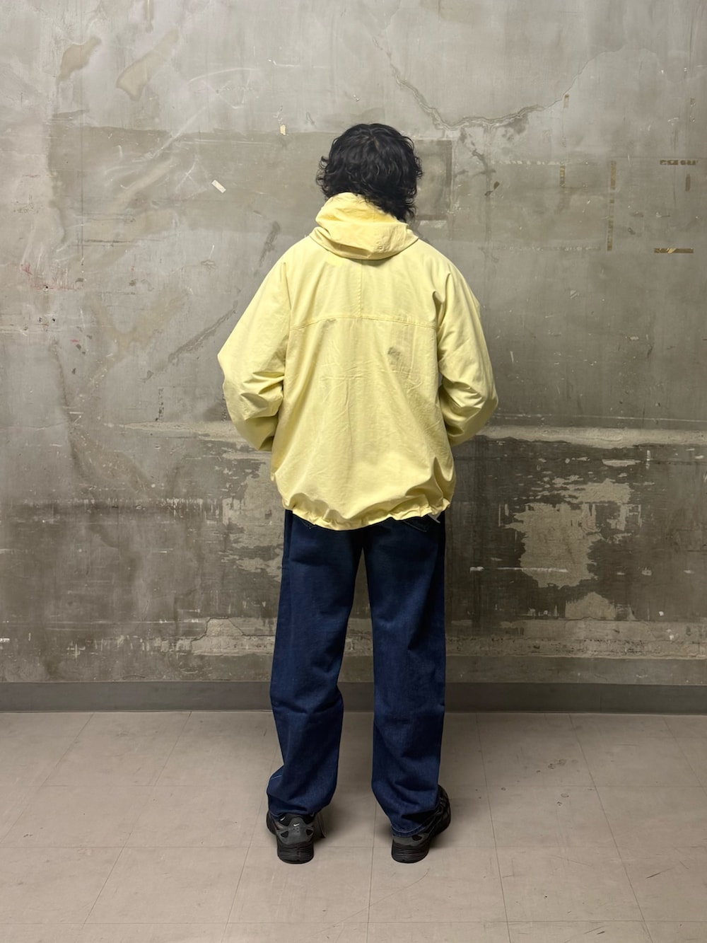 ブルー系のデニムパンツ、イエロー系のナイロンジャケット、ブラック系のスニーカーを着用したメンズの冬コーディネートの3枚目の写真