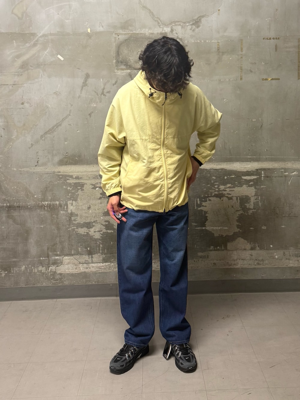 ブルー系のデニムパンツ、イエロー系のナイロンジャケット、ブラック系のスニーカーを着用したメンズの冬コーディネートの5枚目の写真