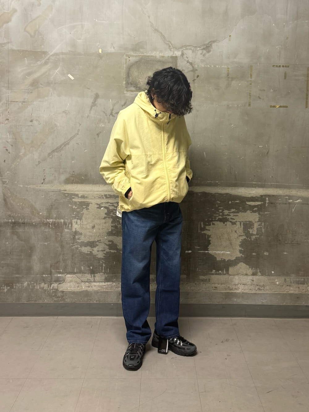 ブルー系のデニムパンツ、イエロー系のナイロンジャケット、ブラック系のスニーカーを着用したメンズの冬コーディネートの2枚目の写真