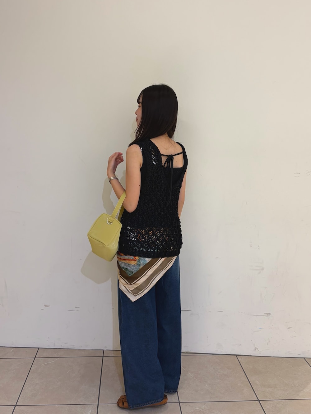 ブラック系のニット/セーター、ブルー系のデニムパンツ、ブラウン系のサンダルを着用したレディースの夏コーディネートの4枚目の写真