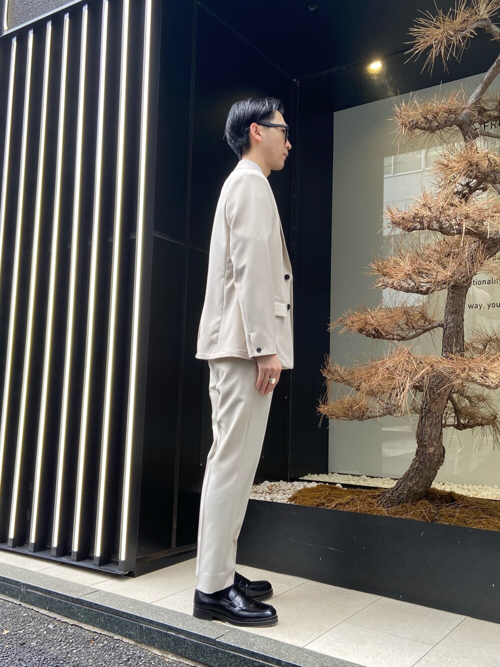 ベージュ系のセットアップ、ベージュ系のスラックス、ブラック系のローファーを着用したメンズの春コーディネートの2枚目の写真