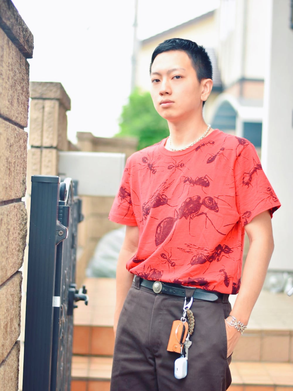 レッド系のTシャツ/カットソー、ブラック系のチノパンツ、ブラック系のブーツを着用したメンズの春コーディネートの2枚目の写真