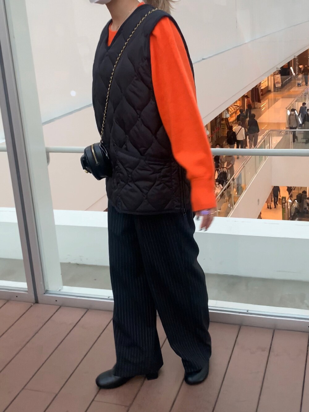 オレンジ系のニット/セーター、ブラック系のショルダーバッグを着用したレディースの秋コーディネートの2枚目の写真