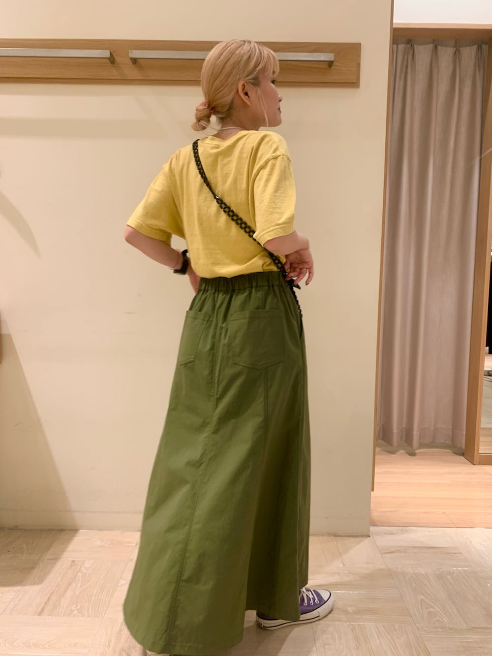 ブラック系のショルダーバッグ、グリーン系のスカート、パープル系のスニーカーを着用したレディースの夏コーディネートの2枚目の写真