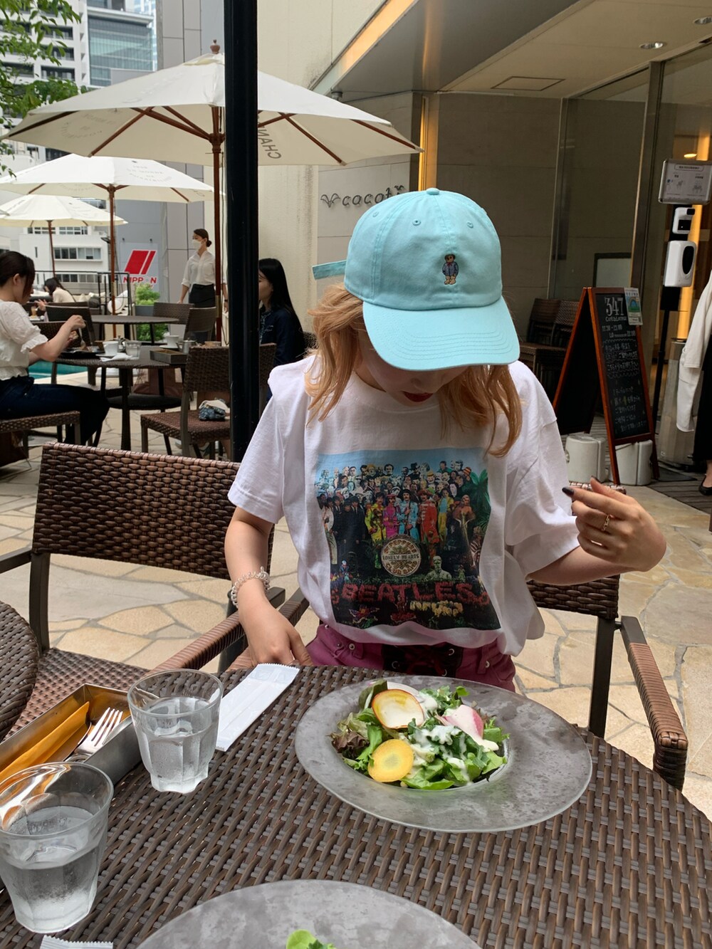 ピンク系のバッグ、パープル系のスニーカー、ホワイト系のTシャツ/カットソーを着用したレディースの夏コーディネートの2枚目の写真