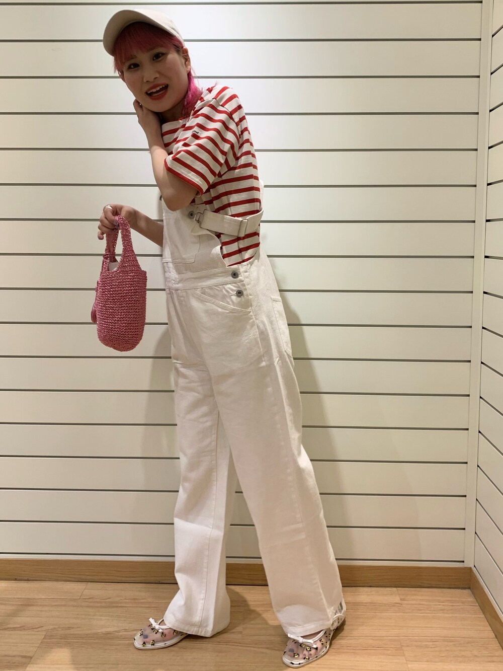 ピンク系のトートバッグ、ホワイト系のサロペット/オーバーオール、ベージュ系のキャップを着用したレディースの春コーディネートの2枚目の写真