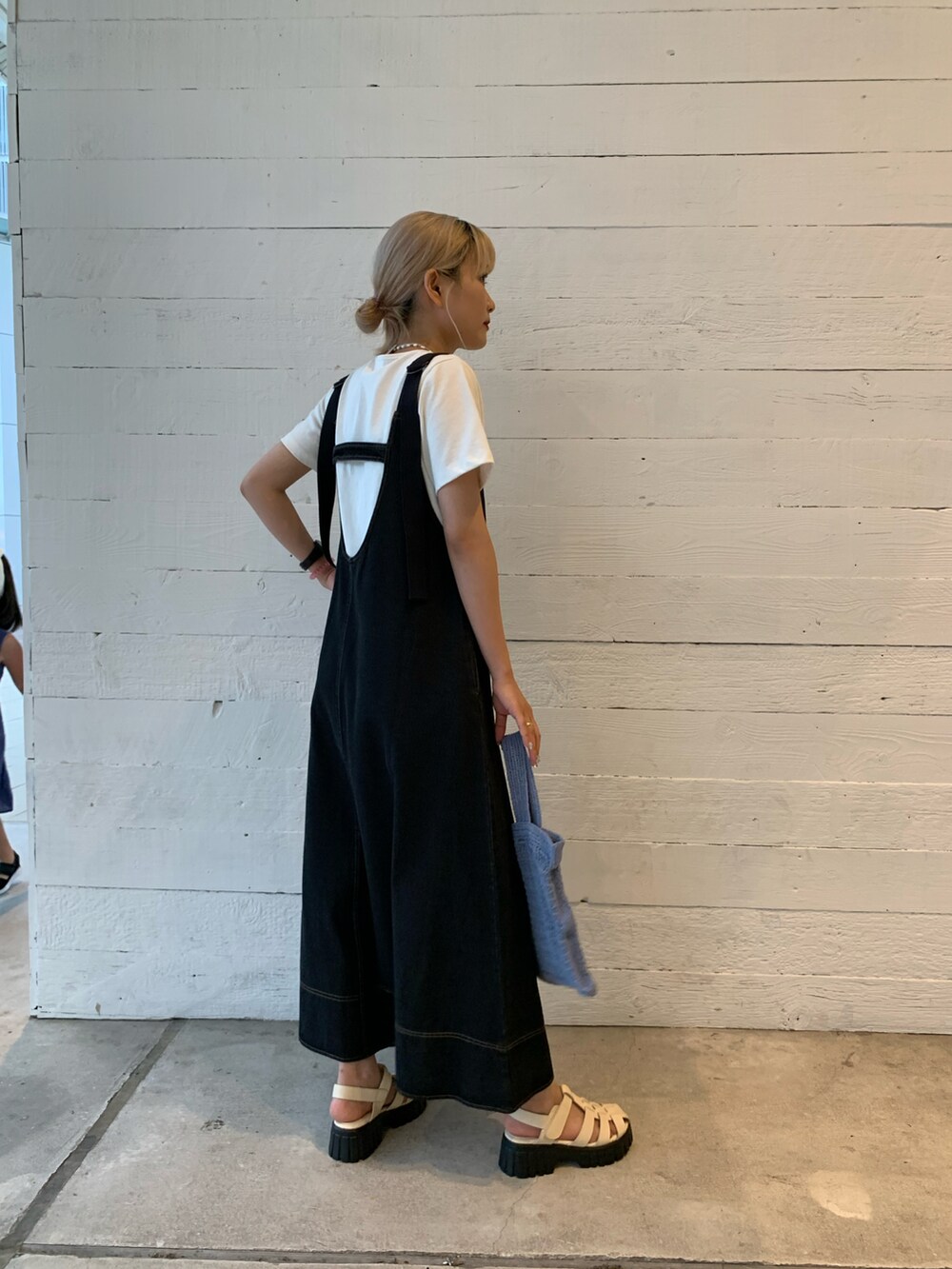 ブラック系のジャンパースカート、ホワイト系のTシャツ/カットソー、ホワイト系のサンダルを着用したレディースの夏コーディネートの2枚目の写真