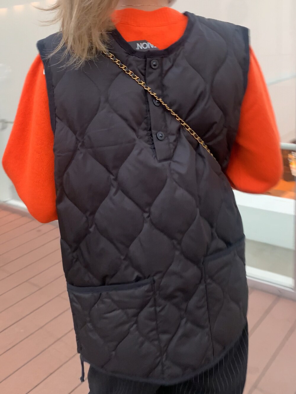 オレンジ系のニット/セーター、ブラック系のショルダーバッグを着用したレディースの秋コーディネートの3枚目の写真