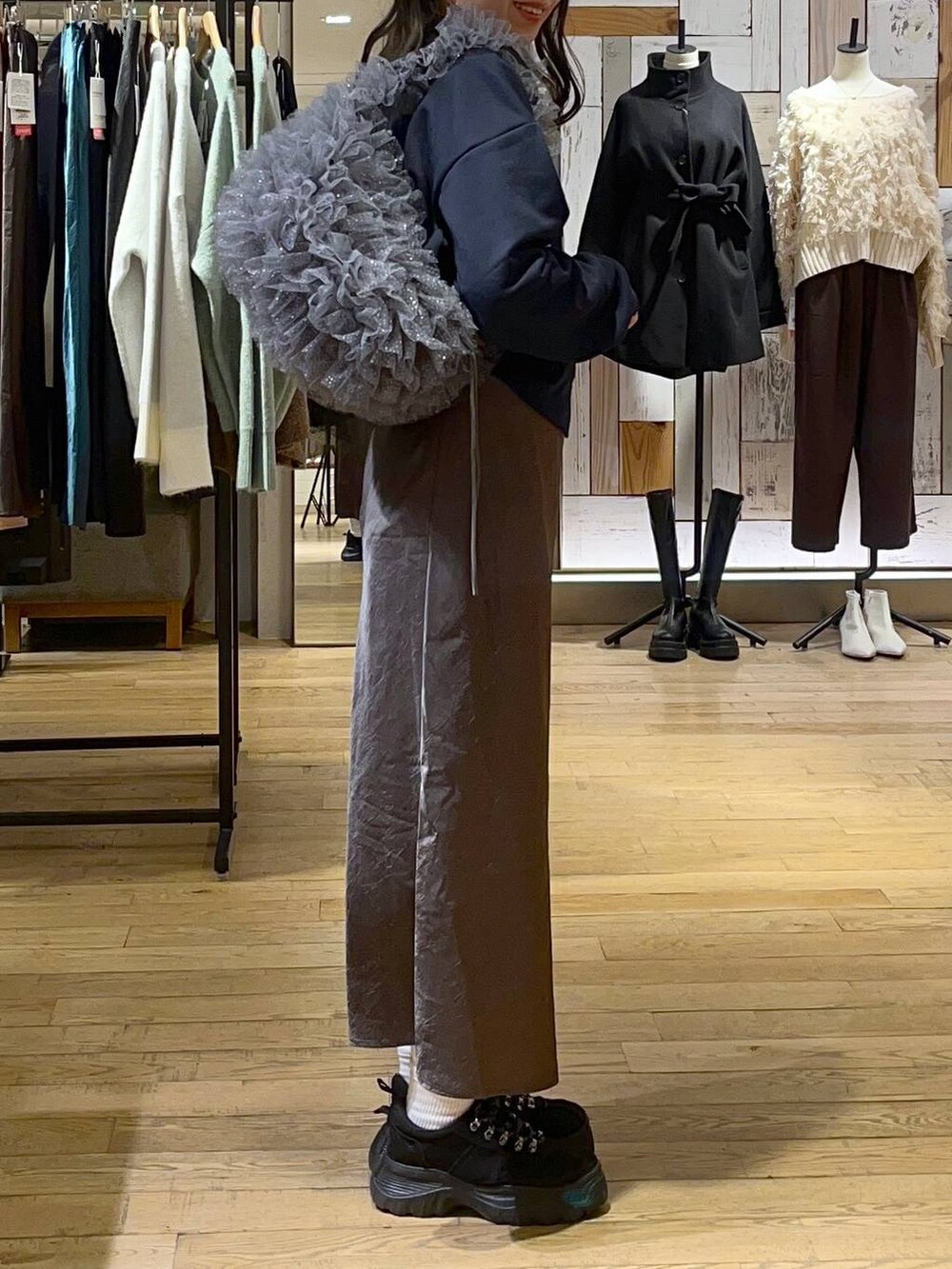 グレー系のスカート、ブラック系のモカシン/デッキシューズ、グレー系のショルダーバッグを着用したレディースの冬コーディネートの2枚目の写真