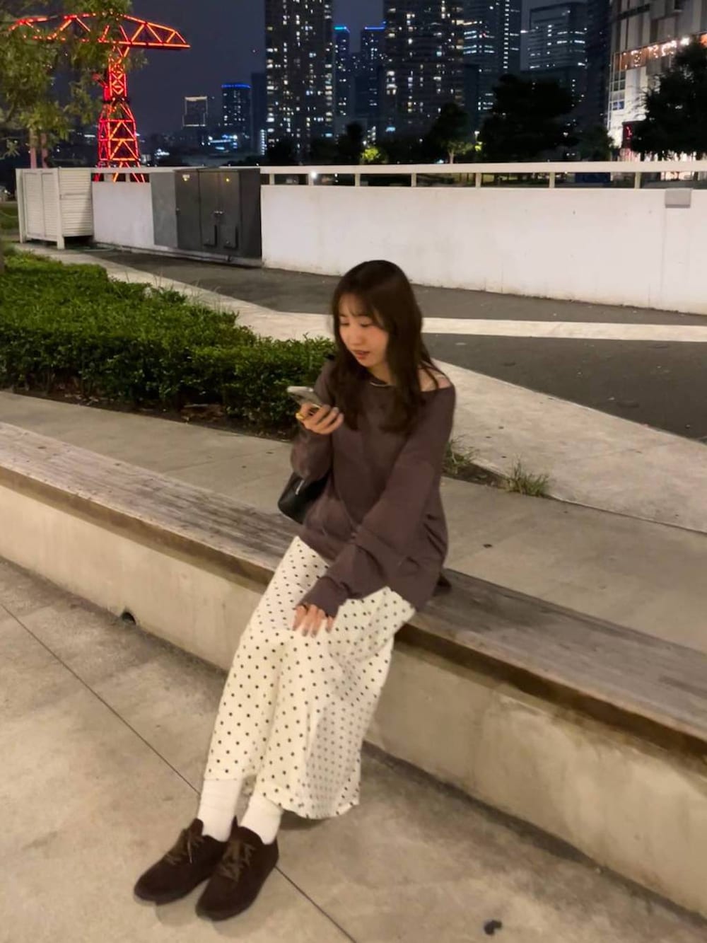 ホワイト系のスカート、ブラウン系のスニーカー、ブラック系のボストンバッグを着用したレディースの秋コーディネートの3枚目の写真