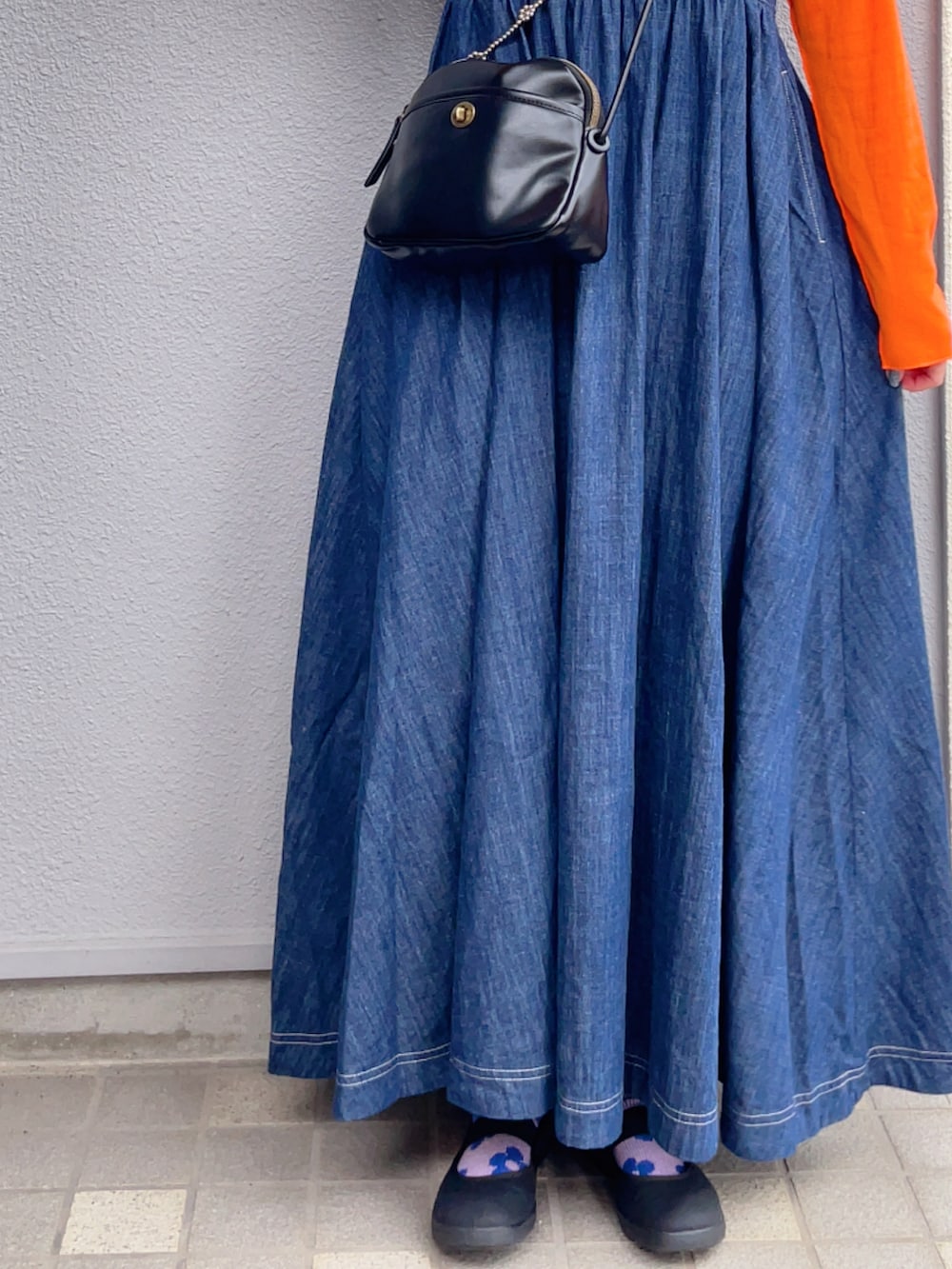 ブラック系のショルダーバッグ、オレンジ系のTシャツ/カットソー、ブルー系のワンピースを着用したレディースの秋コーディネートの2枚目の写真