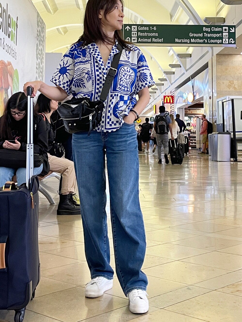 ブルー系のシャツ/ブラウス、ブラック系のメッセンジャーバッグ、ブルー系のデニムパンツを着用したレディースの夏コーディネートの2枚目の写真