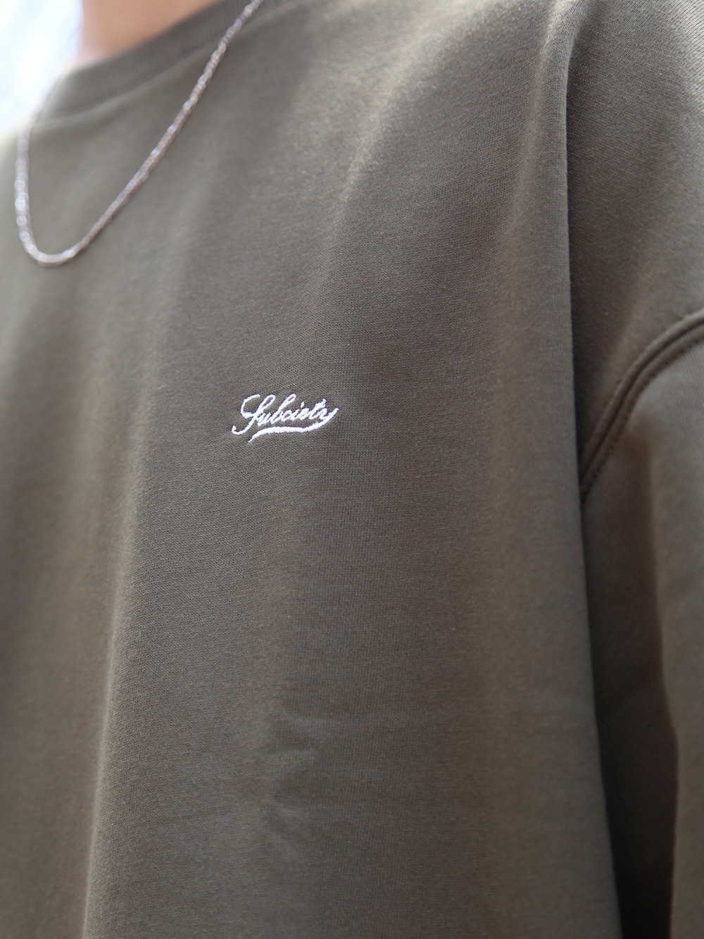 グレー系のカーゴパンツ、グリーン系のTシャツ/カットソー、シルバー系のネックレスを着用したメンズの夏コーディネートの2枚目の写真