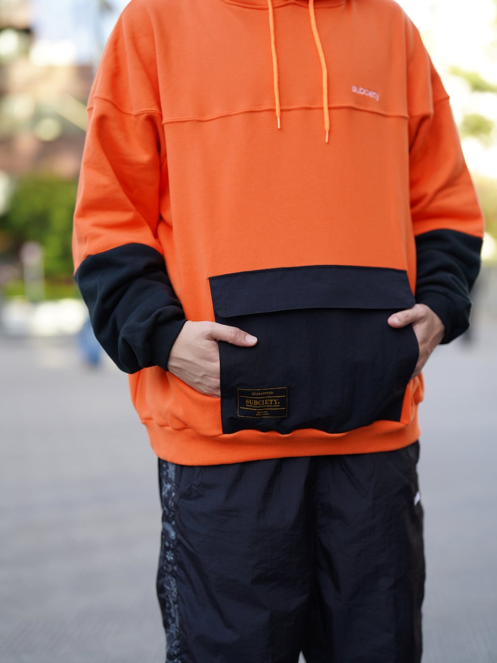 オレンジ系のパーカー、ブラック系のその他パンツ、ブラック系のキャップを着用したメンズの秋コーディネートの2枚目の写真