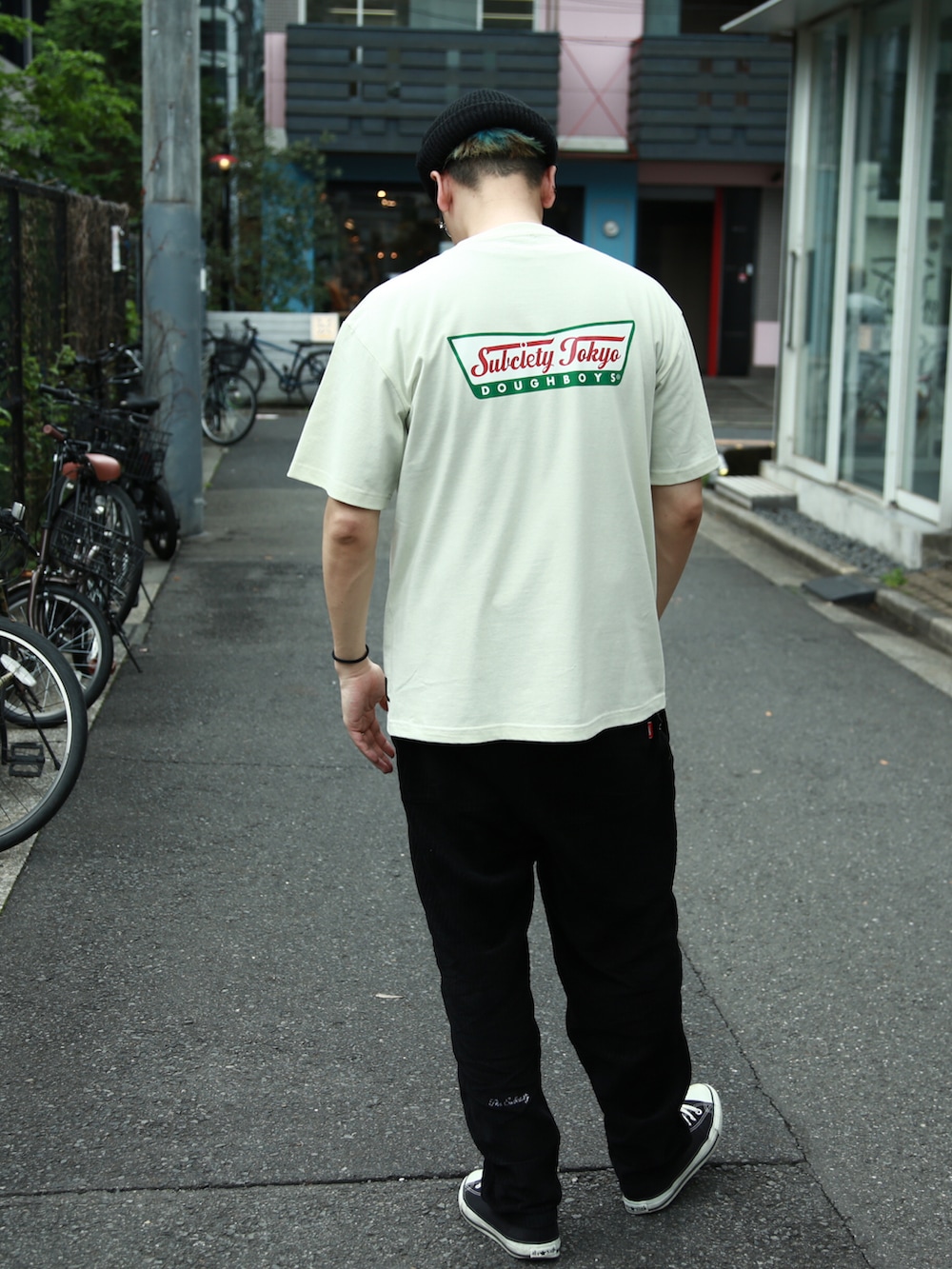 ブラック系のスラックス、グリーン系のTシャツ/カットソー、ブラック系のニットキャップ/ビーニーを着用したメンズの春コーディネートの3枚目の写真
