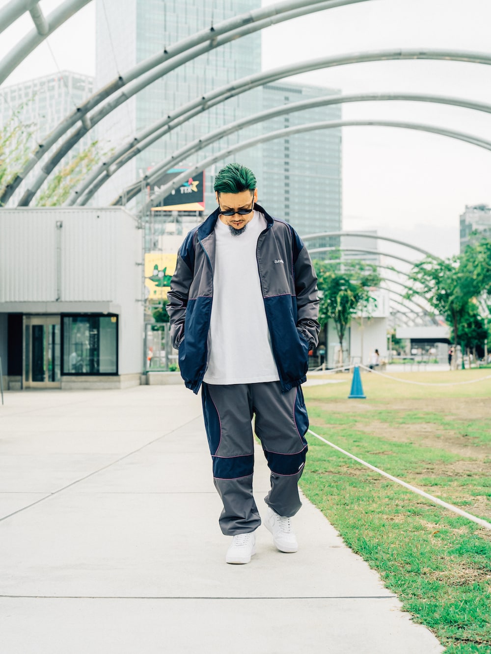 グレー系のその他パンツ、グレー系のナイロンジャケット、ブラック系のサングラスを着用したメンズの夏コーディネートの2枚目の写真